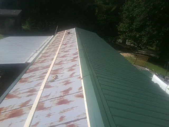 Old rusted panels beside newly installed green metal roofing — Wind Damage Roof Repair by Roofing Brothers in Safety Harbor