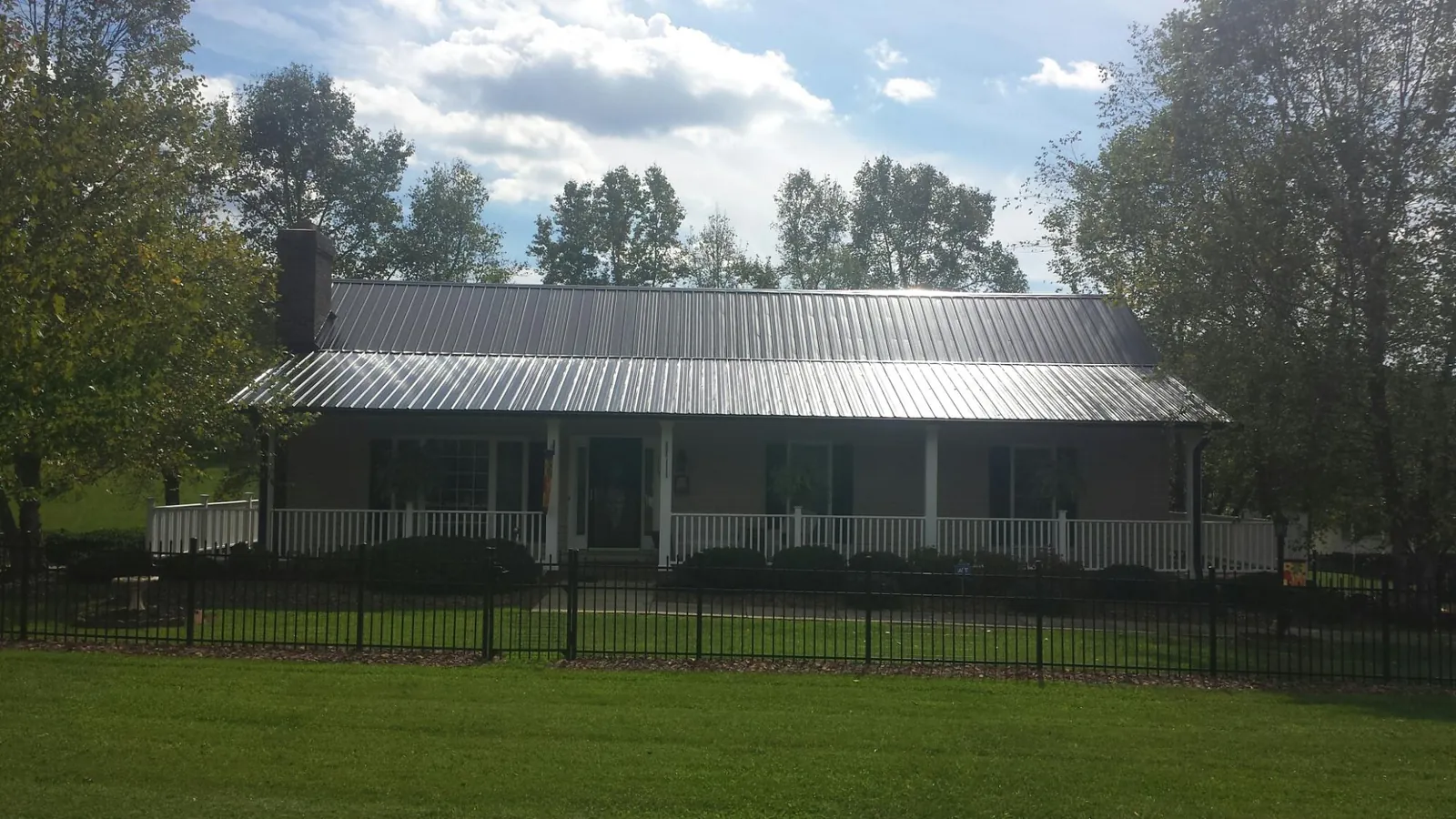 Gray metal roof on a brick ranch with a full width front porch — Gutter Guard Installation work by our crew in Safety Harbor