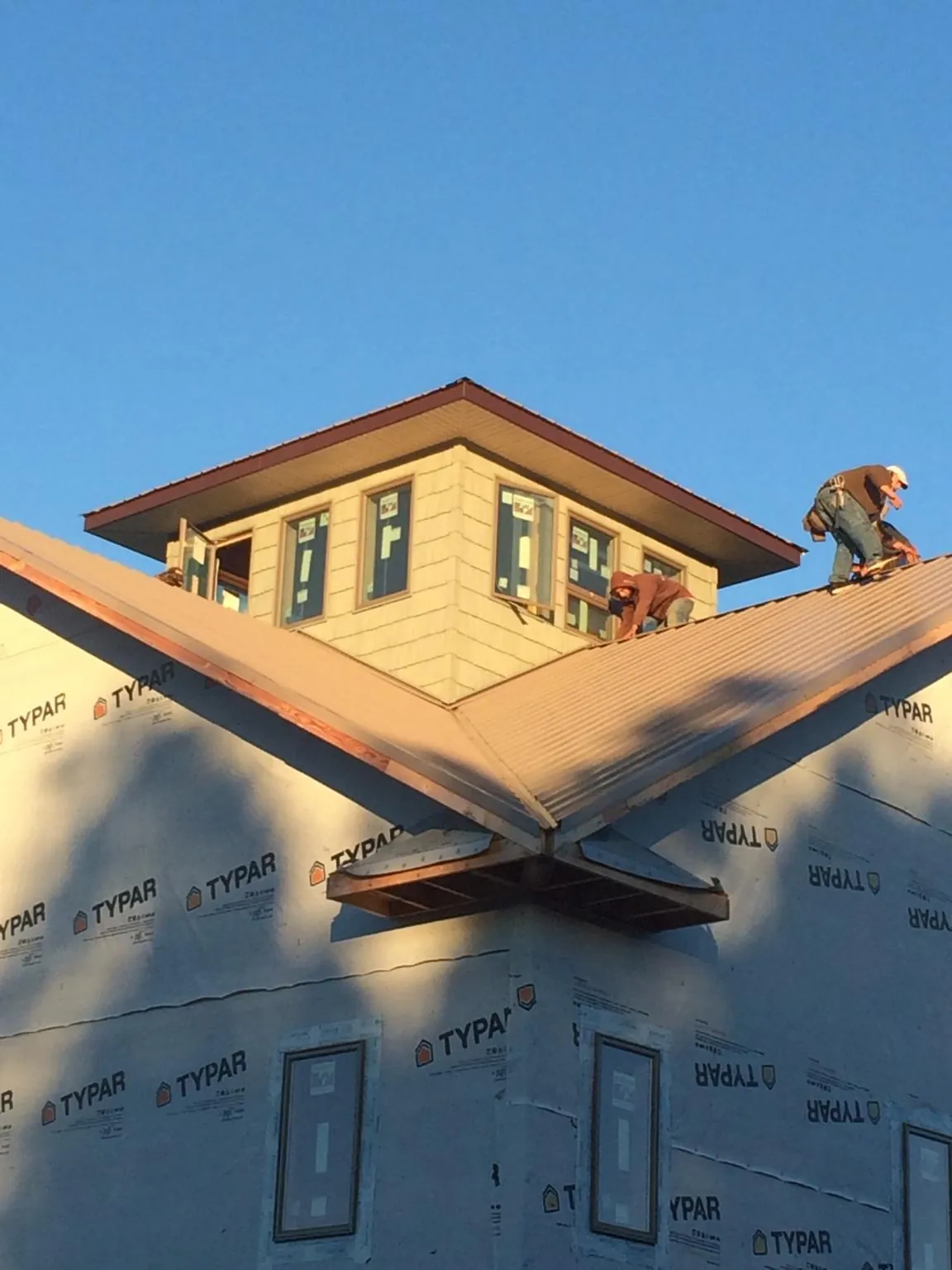 Roofers working around a rooftop cupola on a new metal roof at sunset — Roof Waterproofing in Safety Harbor by Roofing Brothers